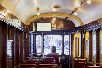 Nainen istuu vanhan raitiovaunun ohjaamossa.