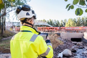 Insinööri tekee muistiinpanoja, taustalla metrojuna.