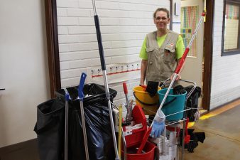 Kiinteistösiivoaja siivouskärryn kanssa.