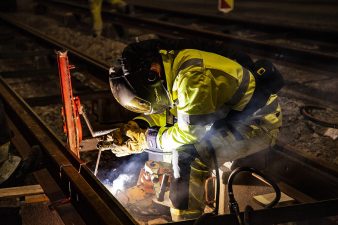 Hitsaaja työssään raitiovaunukiskojen välissä.