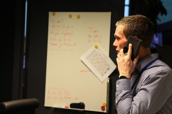 Mies puhuu puhelimessa fläppitaulun edessä.