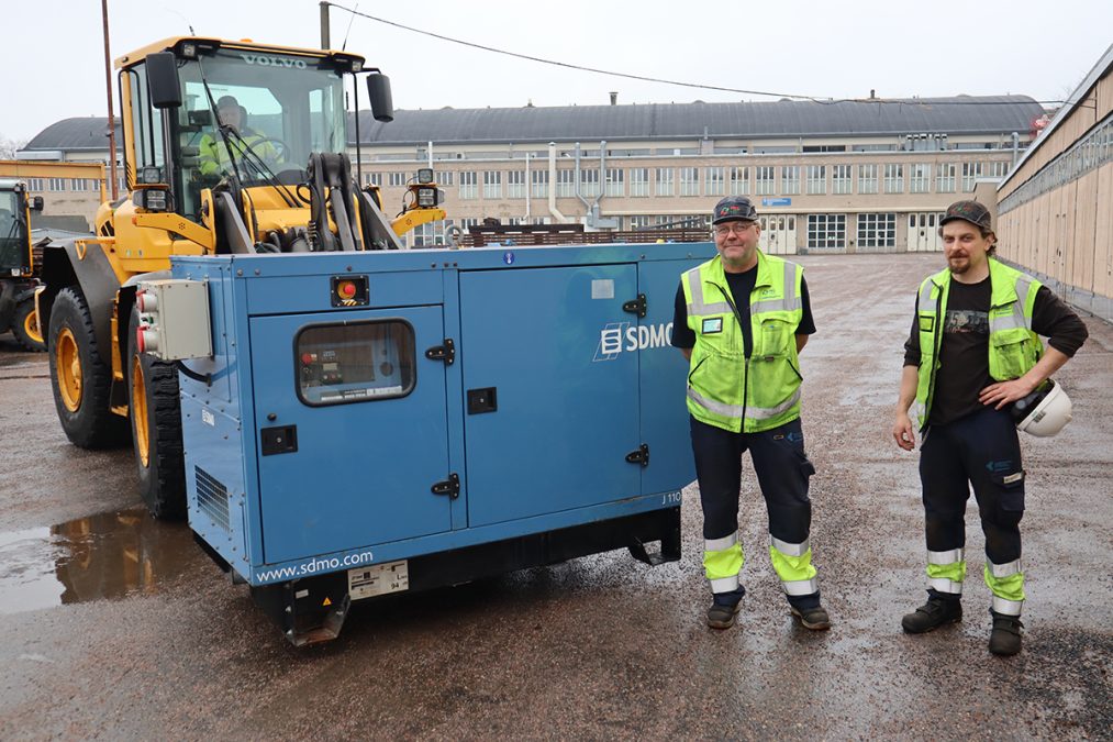 Kaksi miestä generaattorin edessä, joka trukin kyydissä valmiina lastattavaksi rekkaan.