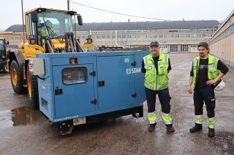 Kaksi miestä generaattorin edessä, joka trukin kyydissä valmiina lastattavaksi rekkaan.