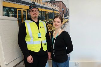 Kesätyöntekijät Jenni ja Santeri seisovat raitiovaunukuvan edessä.