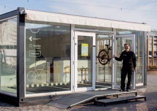 Henkilö vilkuttaa pyörien huoltoon tarkoitetun kontin ovelta.
