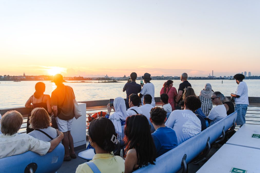 Matkustajia Suomenlinnan lautalla ilta-auringossa.