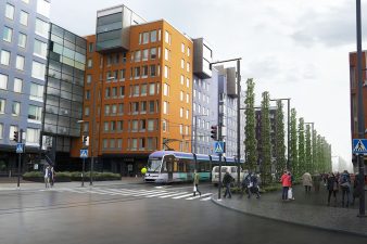 Raitiovaunu Vantaan Kielotiellä. Köynnöspylväitä, rakennuksia ja jalankulkijoita.