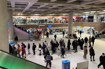 Rautatientorin metroaseman kompassitasolla eli lippuhallissa matkustajia, taustalla liikkeitä.