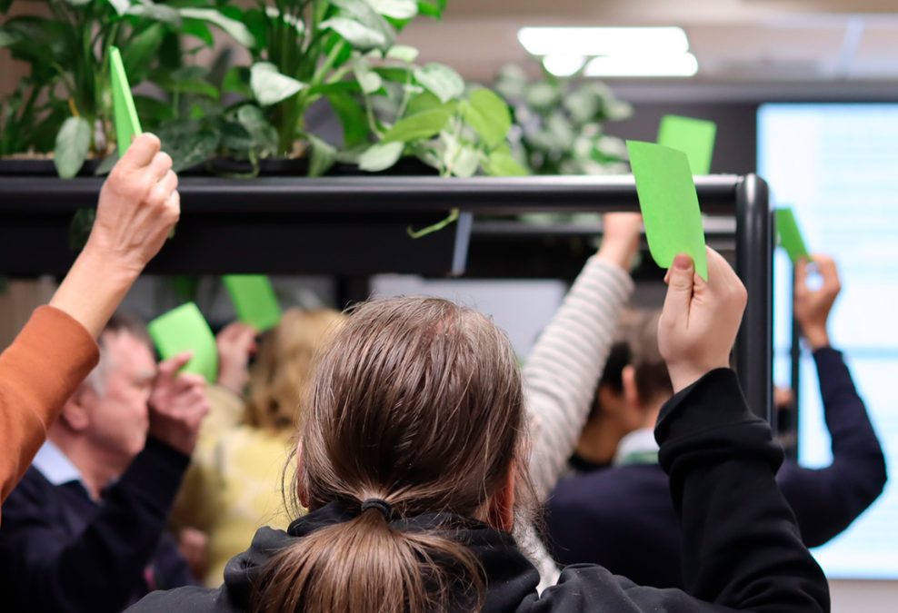 käsiä ylös nostettuina, jotka pitelevät vihreitä post-it -lappuja.