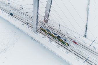 Raitovaunu ajaa lumisessa maisemassa sillan yli.