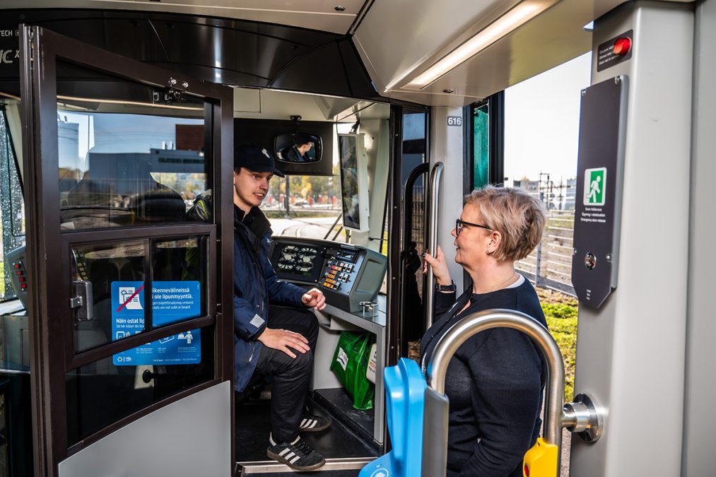 Kaksi Kaupunkiliikenteen työntekijää juttelee raitiovaunun ohjaamossa.