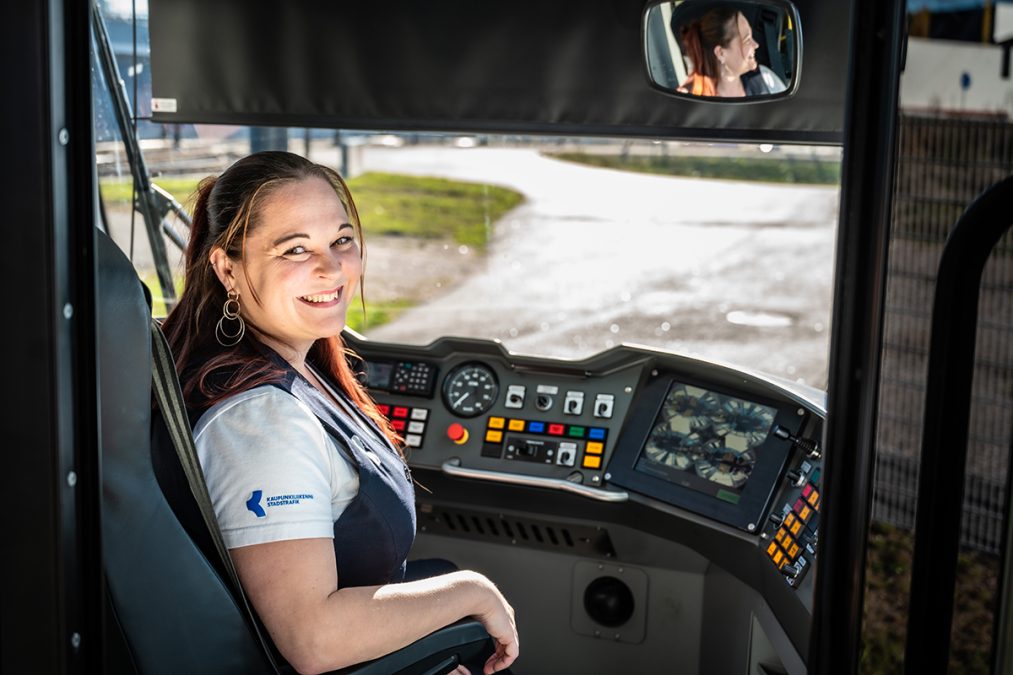 Nainen hymyilee raitiovaunun ohjaamossa.