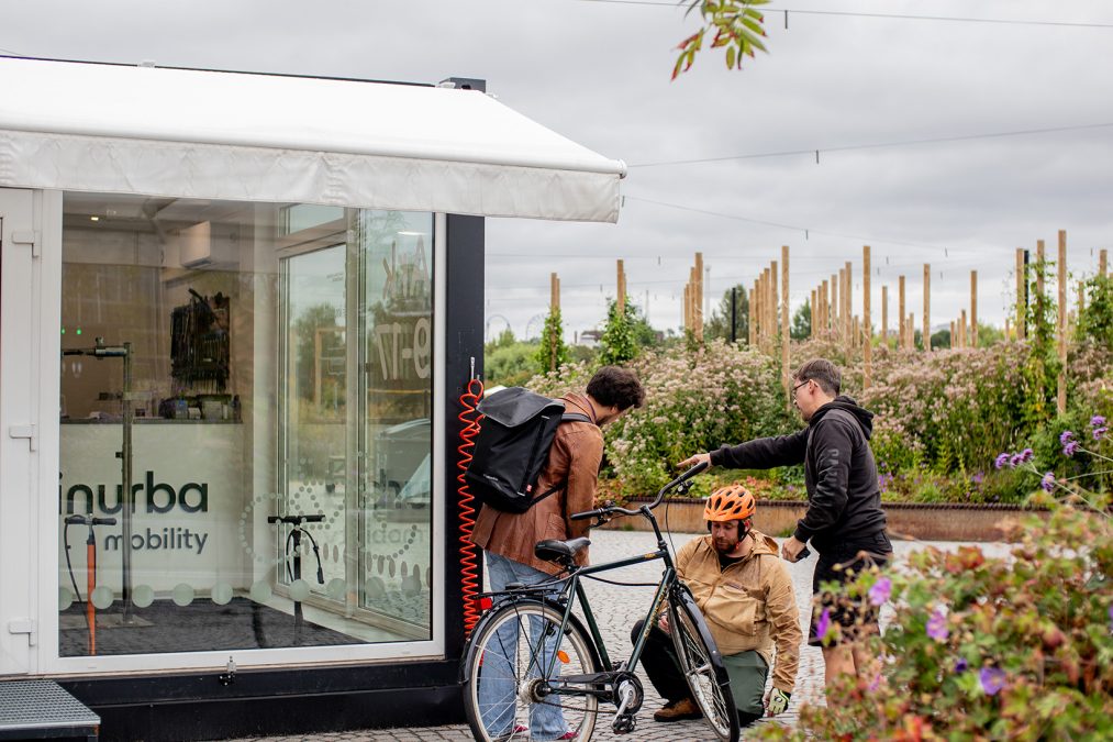 Henkilö pumppaa ilmaa pyörän renkaaseen ja toinen seisoo vieressä.