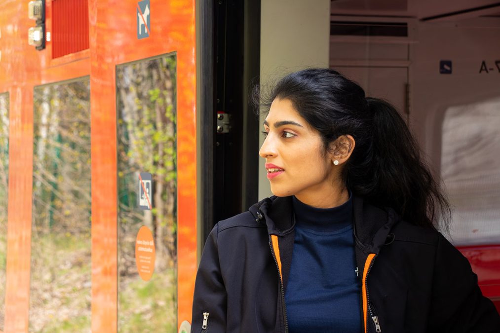 Metro driver standing next to the door of a metro train.