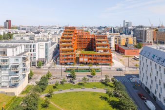 Raitiovaunu kaupunkiympäristössä kerrostalojen ja puiston ympäröimänä.