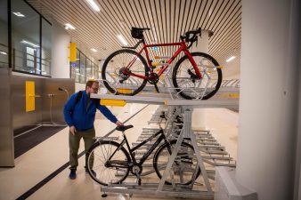 Ihminen asettaa pyörää kaksikerroksiseen pyörätelineeseen.