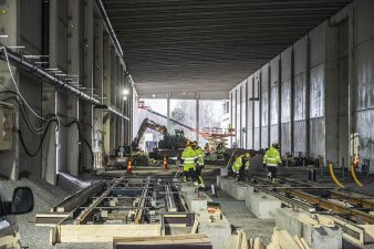 Työntekijöitä keskeneräisessä varikkohallissa raitiotiekiskojen luona.