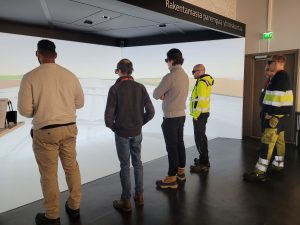 Ihmisiä selin tutustumassa uuteen varikkoon virtuaalisesti.
