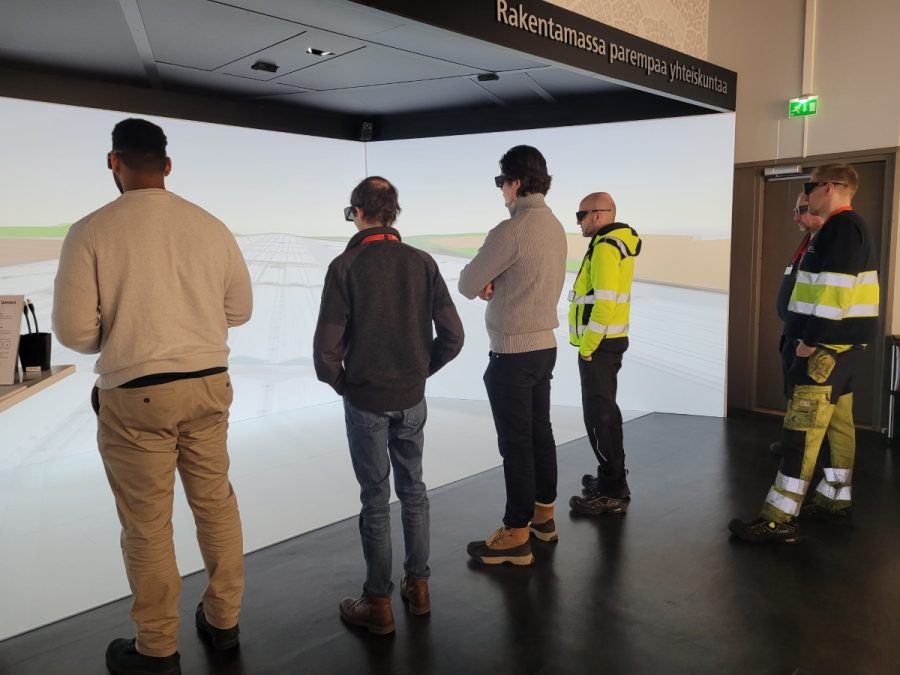 Ihmisiä selin tutustumassa uuteen varikkoon virtuaalisesti.