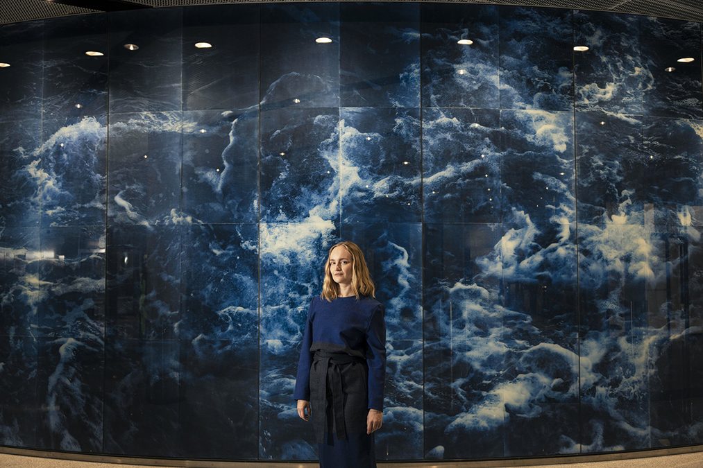 Taitelija Anna Niskanen seisoo valokuvateoksensa edessä. 